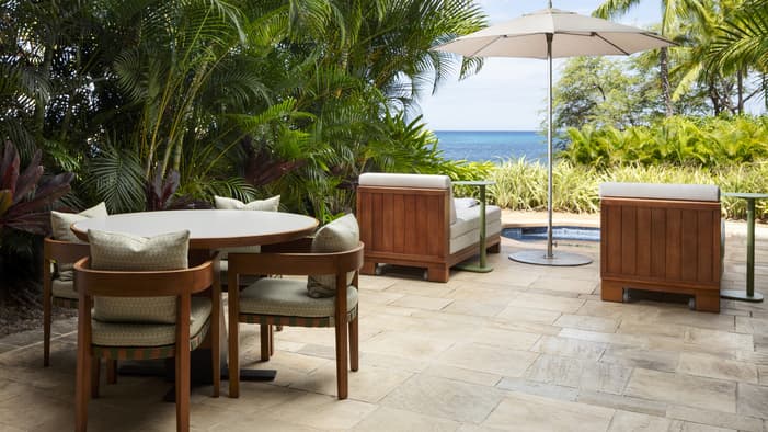 Private terrace with an outdoor hot tub, lounge seating, tropical plants, and ocean views